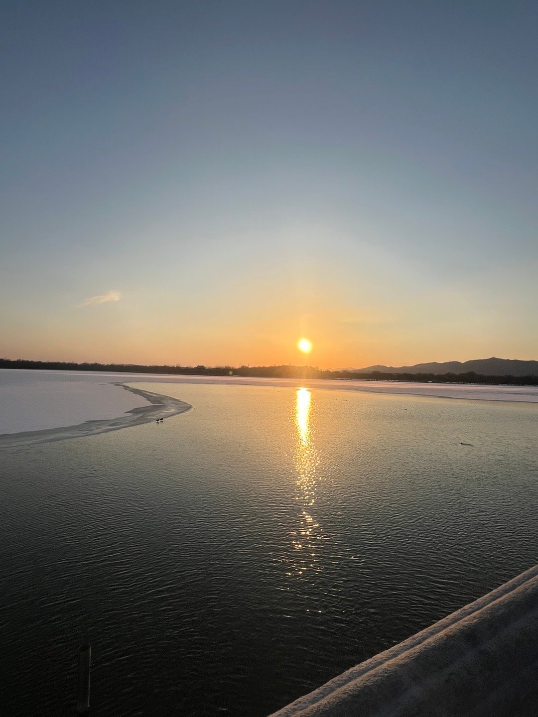 大雪过后的北京又恢复了晴空万里。此刻已临近傍晚，颐和园的昆明湖在落日余晖的照耀下