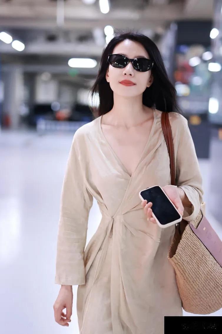 高圆圆北京机场亮相，米色深V裙优雅迷人，长发飘逸，气质出众。