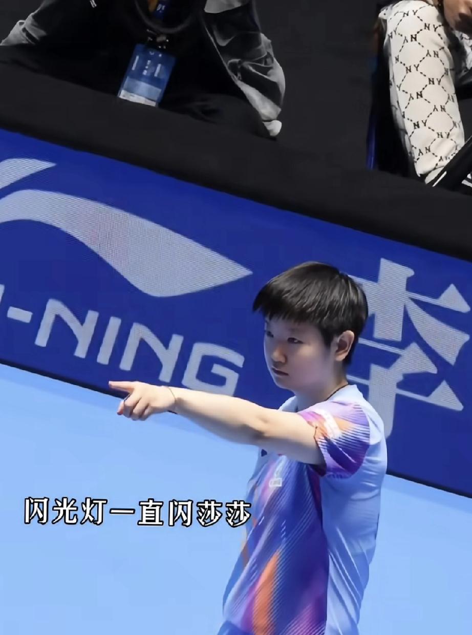 莎莎单手指着闪光灯的方向,表情严肃。
真不理解，看比赛就好好看，为什么要打开对球