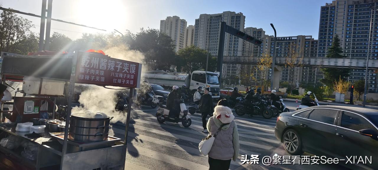 冬日生活打卡季早上路旁的早点摊散发着热气。在一旁，人们匆匆赶路。街道上，车水马龙