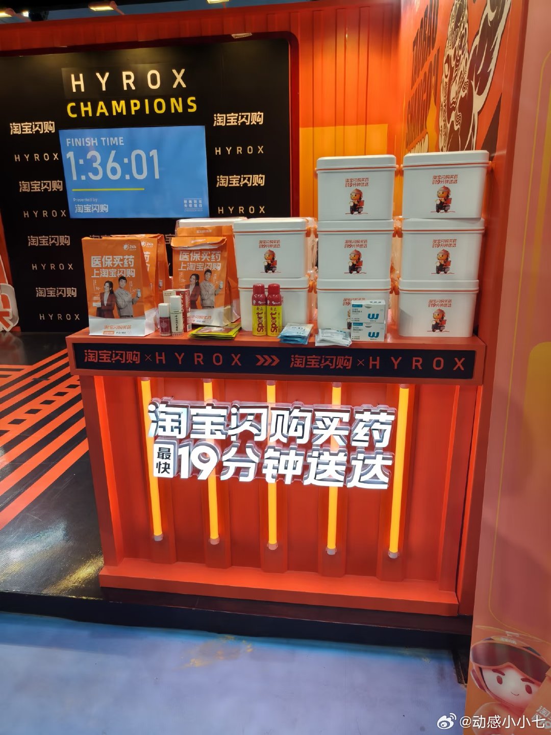 橙红光影流淌在展台边缘，HYROX方盒静静堆叠，印着小小拳击手，仿佛藏着整座城市