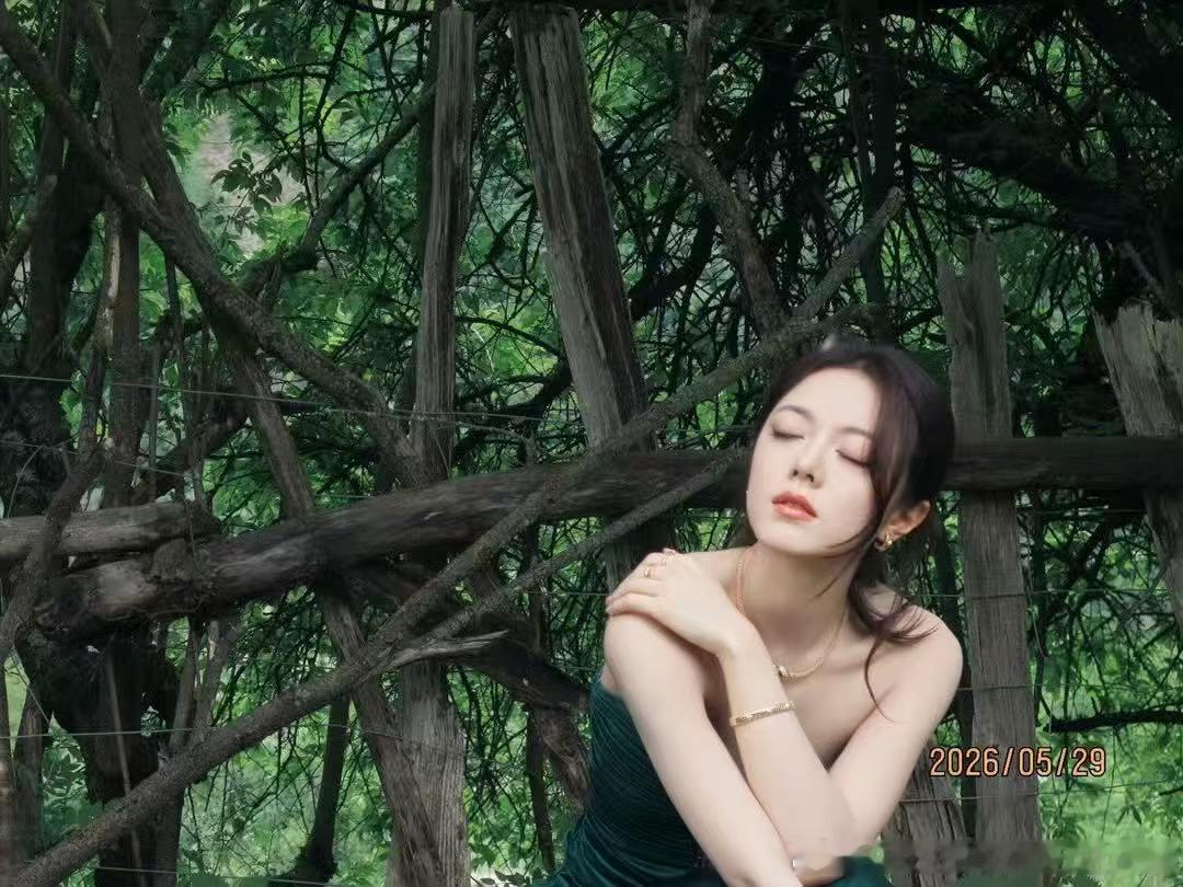 闯入九寨沟的绿野秘境，赵今麦用一袭墨绿长裙续写浪漫。缎面光泽与草木清香相融，雏菊