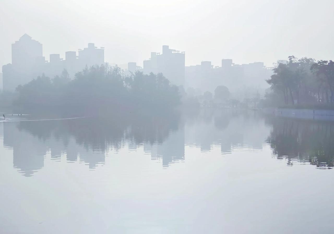 晨雾笼罩下的城市湖景，宁静而神秘。