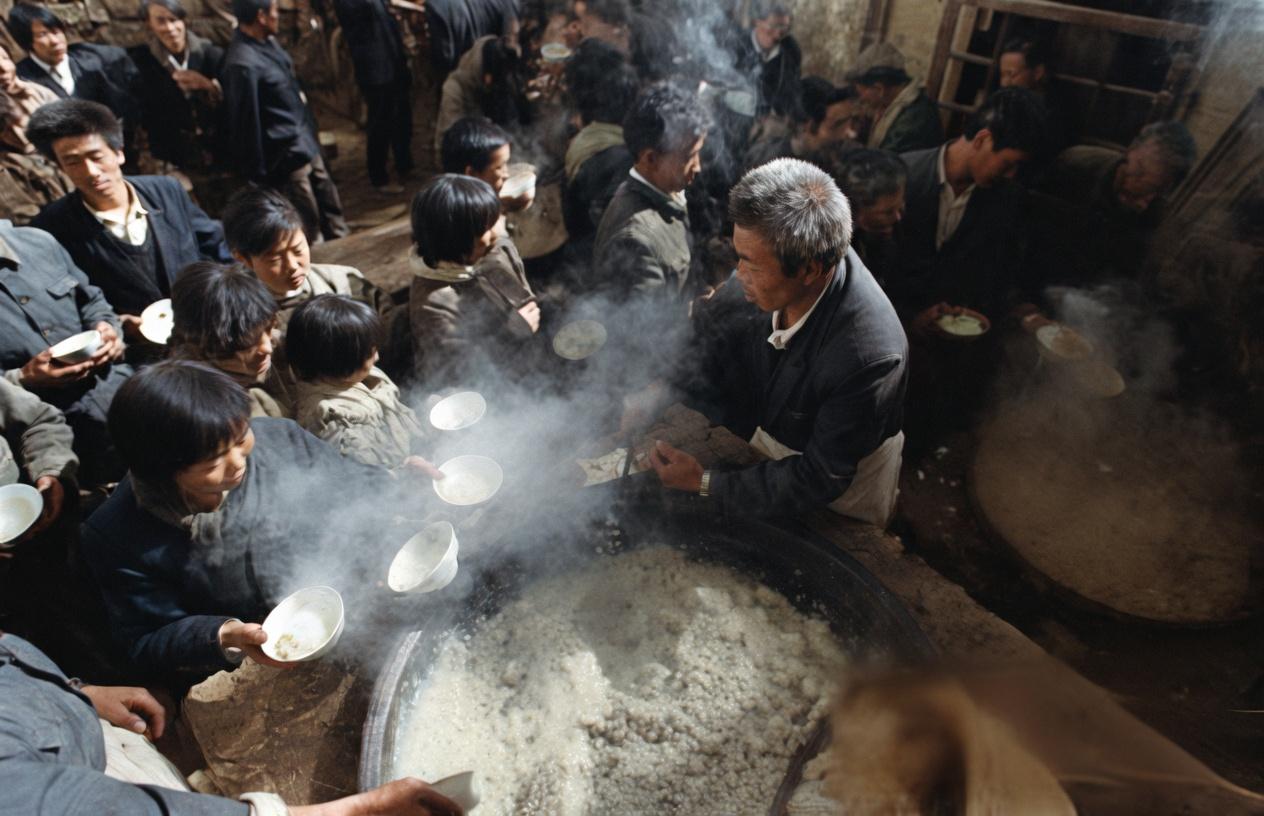 80年代后农村庙会，热气腾腾的巨型铁锅、围满的村民、手里攥着的粗瓷碗，等着盛那顿