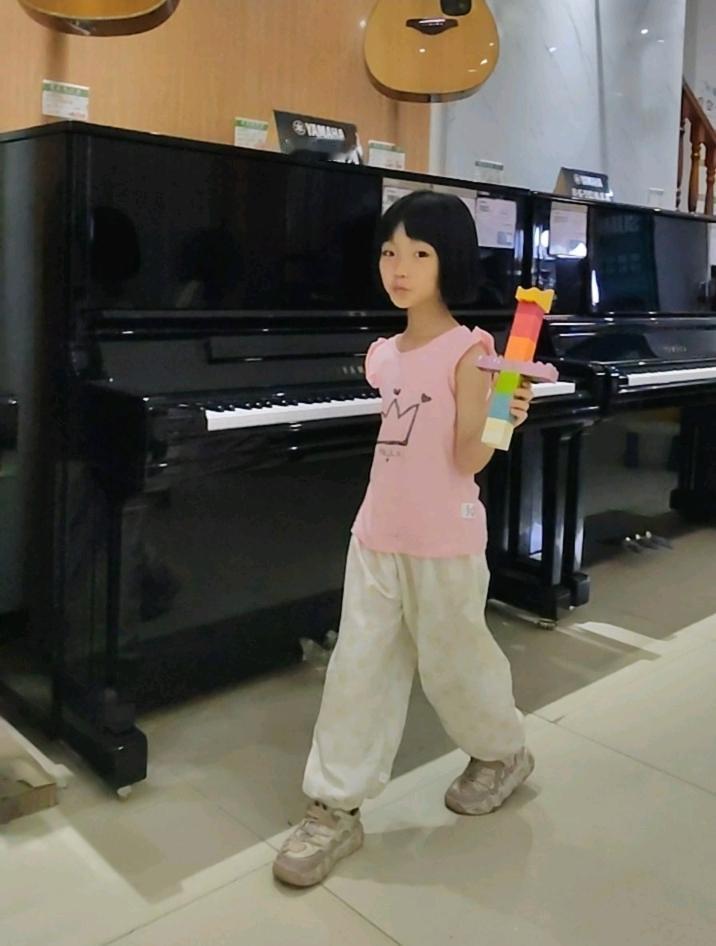 琴行里，抱着积木宝剑的小女孩，和身后静静立着的钢琴，形成了一种奇妙的对比。

一