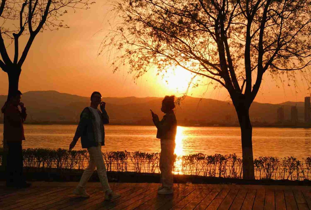 坐在晋阳湖东岸，等着夕阳慢慢西沉，湖边有一棵垂柳树，一会一个美女在夕阳留影感觉很