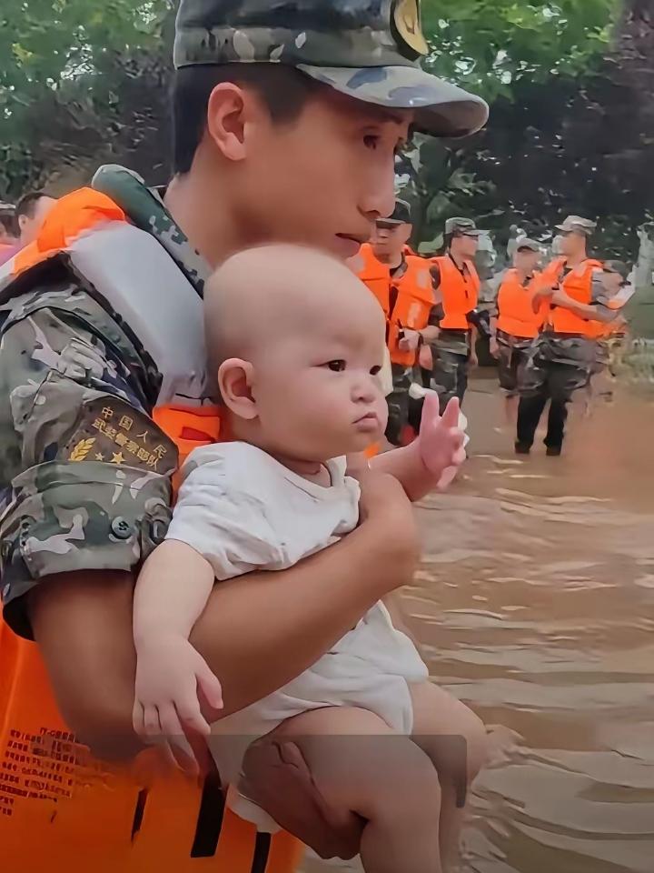 洪水中抱着孩子的解放军战士也还是个孩子，那张稚气未脱的脸告诉我们，他也是父母还没
