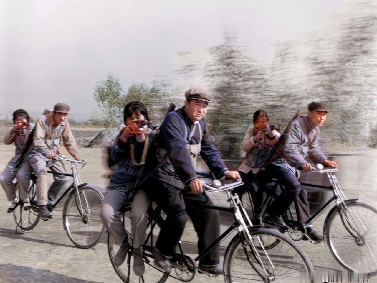 1975年，在厂区外的操场上，3名男民兵奋力蹬着自行车，车后座上的女民兵举枪瞄准