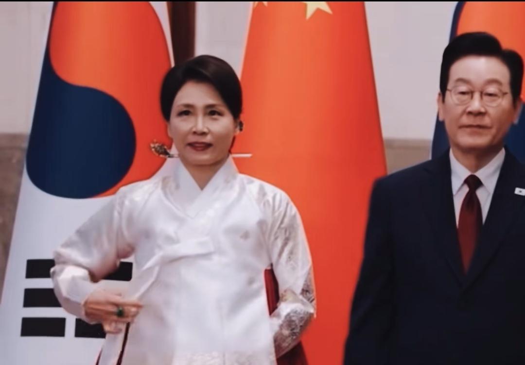 红毯上，那抹红色裙摆划破空气——白色上衣紧贴，绿宝石戒指冷光一闪。
双手始终藏袖