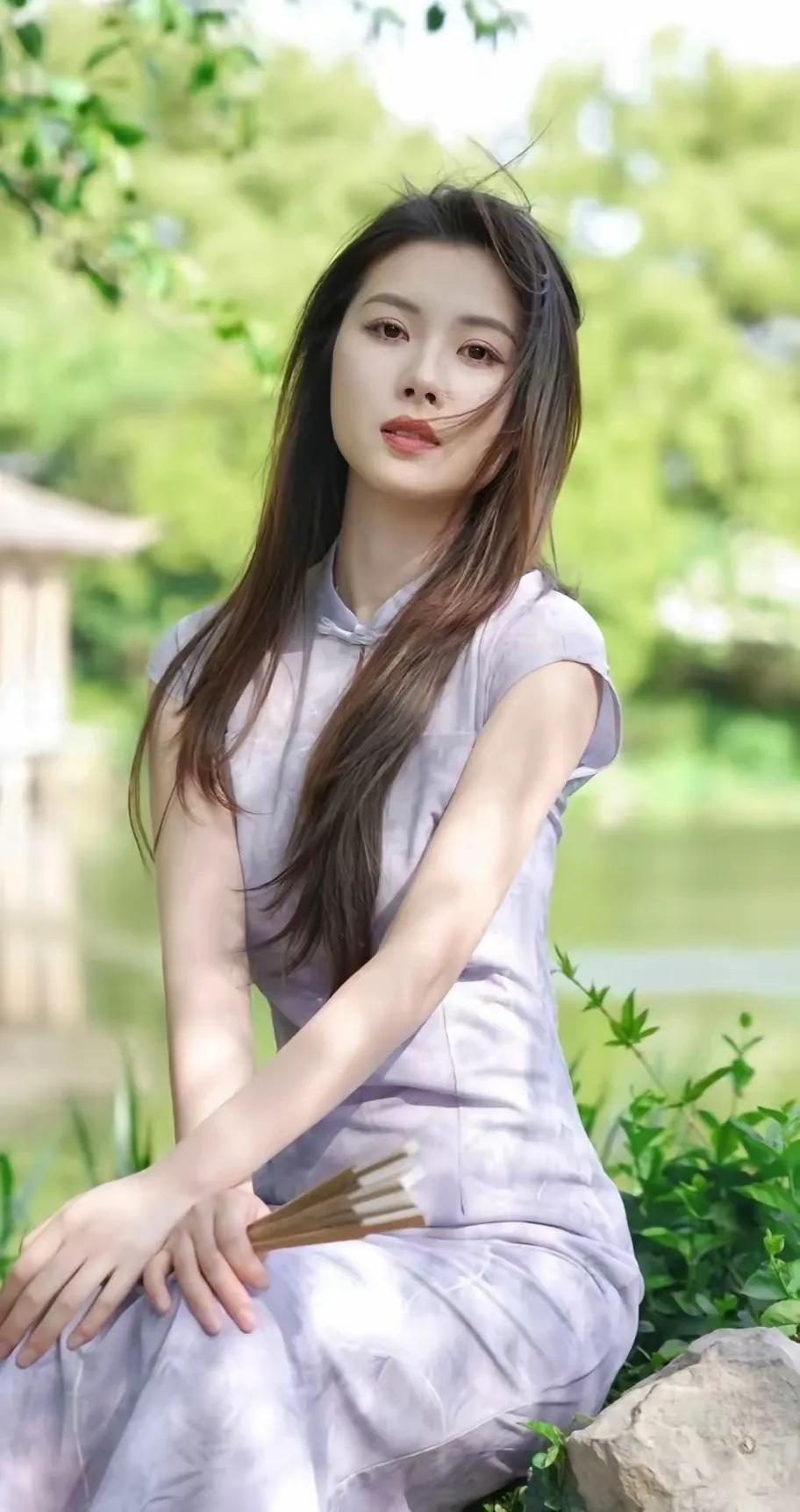 古风少女，静坐绿意中，手持团扇，悠然自得。