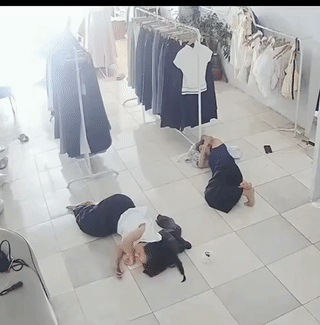 两名女子正躺在服装店里的地上午休，这时一只老鼠突然窜出来钻进了其中一名女子的裤腿