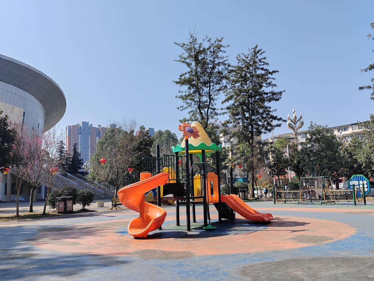 阳光灿烂的体育馆广场上，滑梯与秋千色彩缤纷，孩子们欢快的笑声，令人心情舒畅。🌞