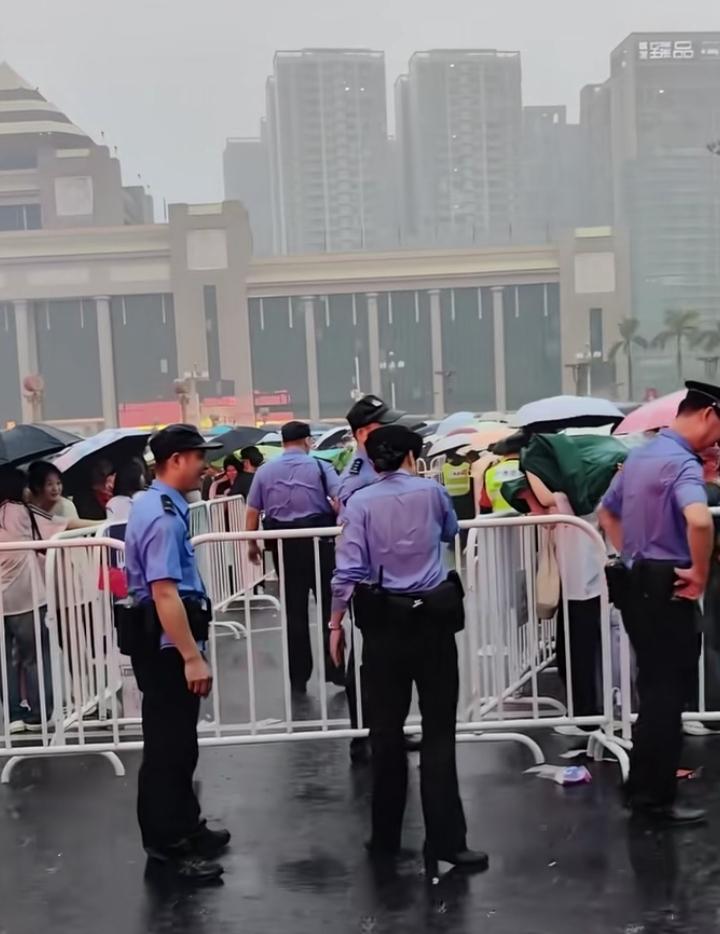 即便大雨倾盆，也丝毫浇不灭众人心中滚烫的爱国热忱。广场上不少民众自发撑伞伫立，静