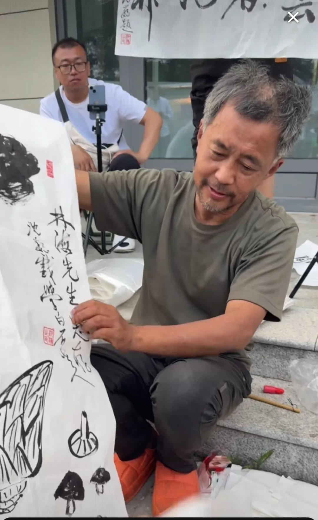 这是近期流浪大师沈巍作画的场景。
最近很多人向“流浪大师”沈巍求书画，希望能获得