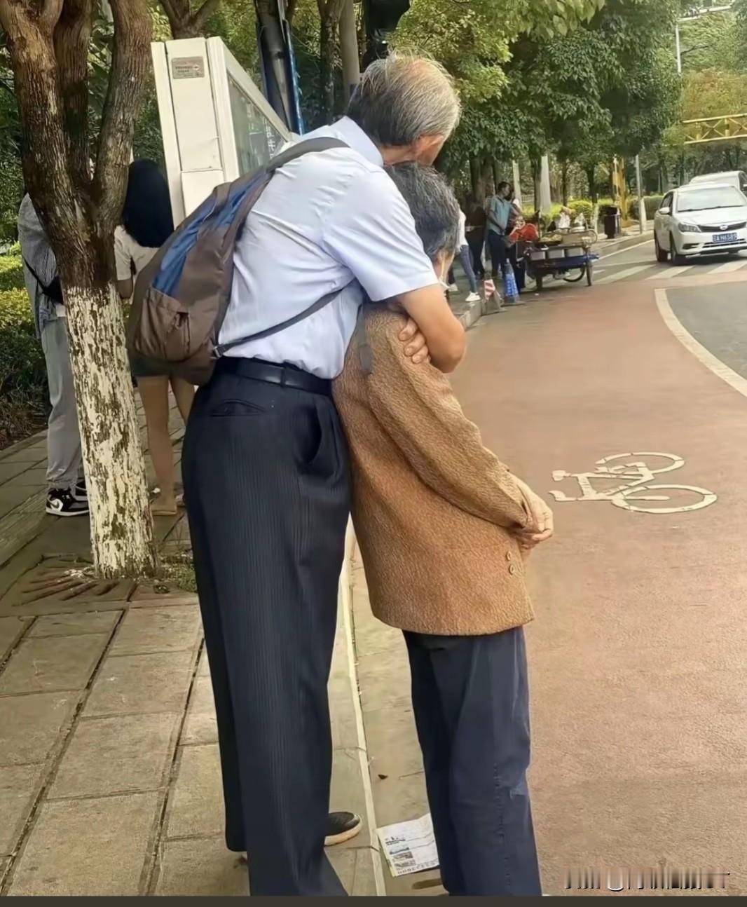 街头一个拥抱，道尽半生相伴的深情

城市繁忙的路边，来往行人步履匆匆，一对老年夫