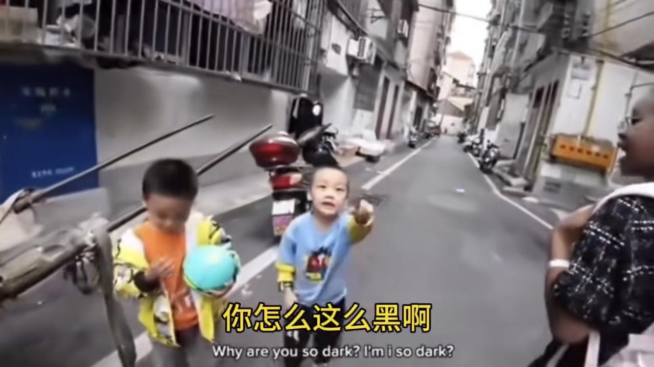 一位来自非洲的黑人男子和他的混血黑人女儿以及他的中国丈母娘走在路上，路边一位中国