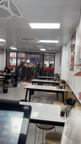 刚开始还以为这群女兵要进店里吃饭呢？
原来她们只是站在店门口集合整理队伍？