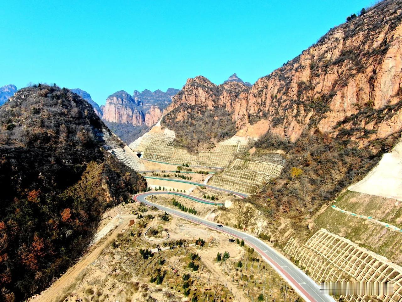 山区的旅游公路蜿蜒曲折、从照片上看很壮观，但是在修路过程中施工人员付出的辛苦甚至