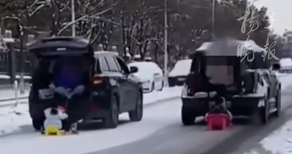 徐州两辆汽车拉雪橇载着孩子在路上滑雪，视频显示：2名儿童无保护措施，大人在后备箱持手机拍摄；交警回应