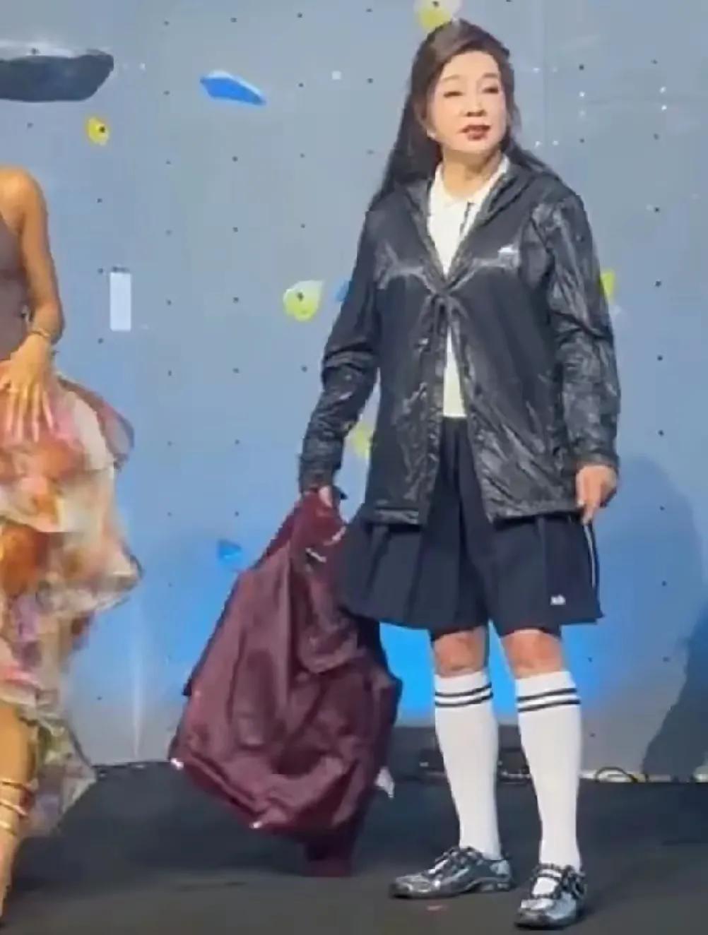 这一身行头，上身长款皮衣，下身学生短裙，和脚套泰妹袜，手上提着个大口袋，这装扮宛