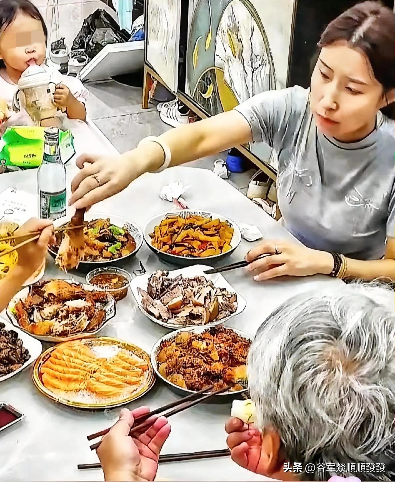 一家6口人正在饭桌上吃饭，儿子夹起盘子里最大的一个鸡腿，递给妈妈让她吃，妈妈连忙