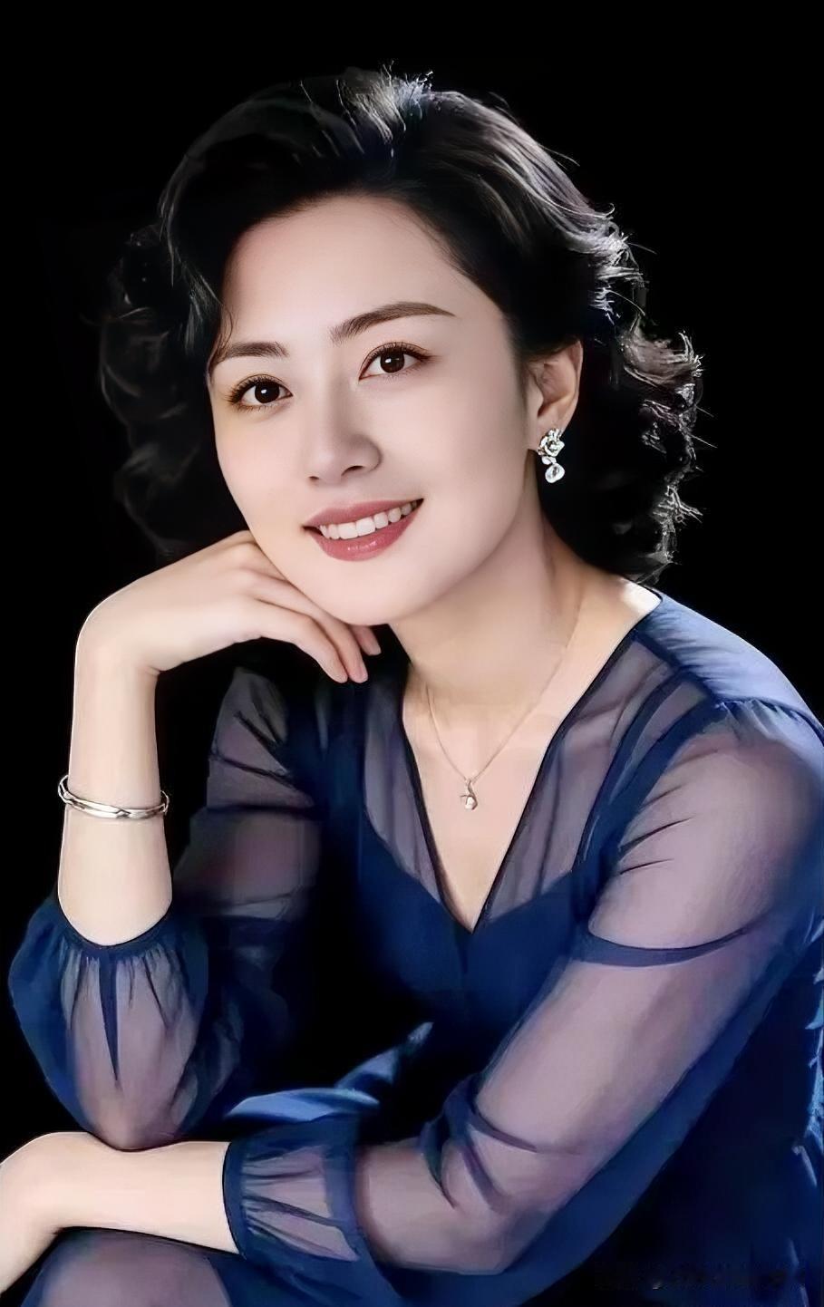 深蓝纱衣掩不住温婉笑意，托腮浅笑间，自信从容自成风景。