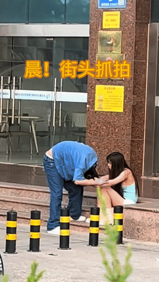 这是网友清晨在街头拍到的一对年轻的小情侣因为闹矛盾正在相互拉扯打架？
可以看到: