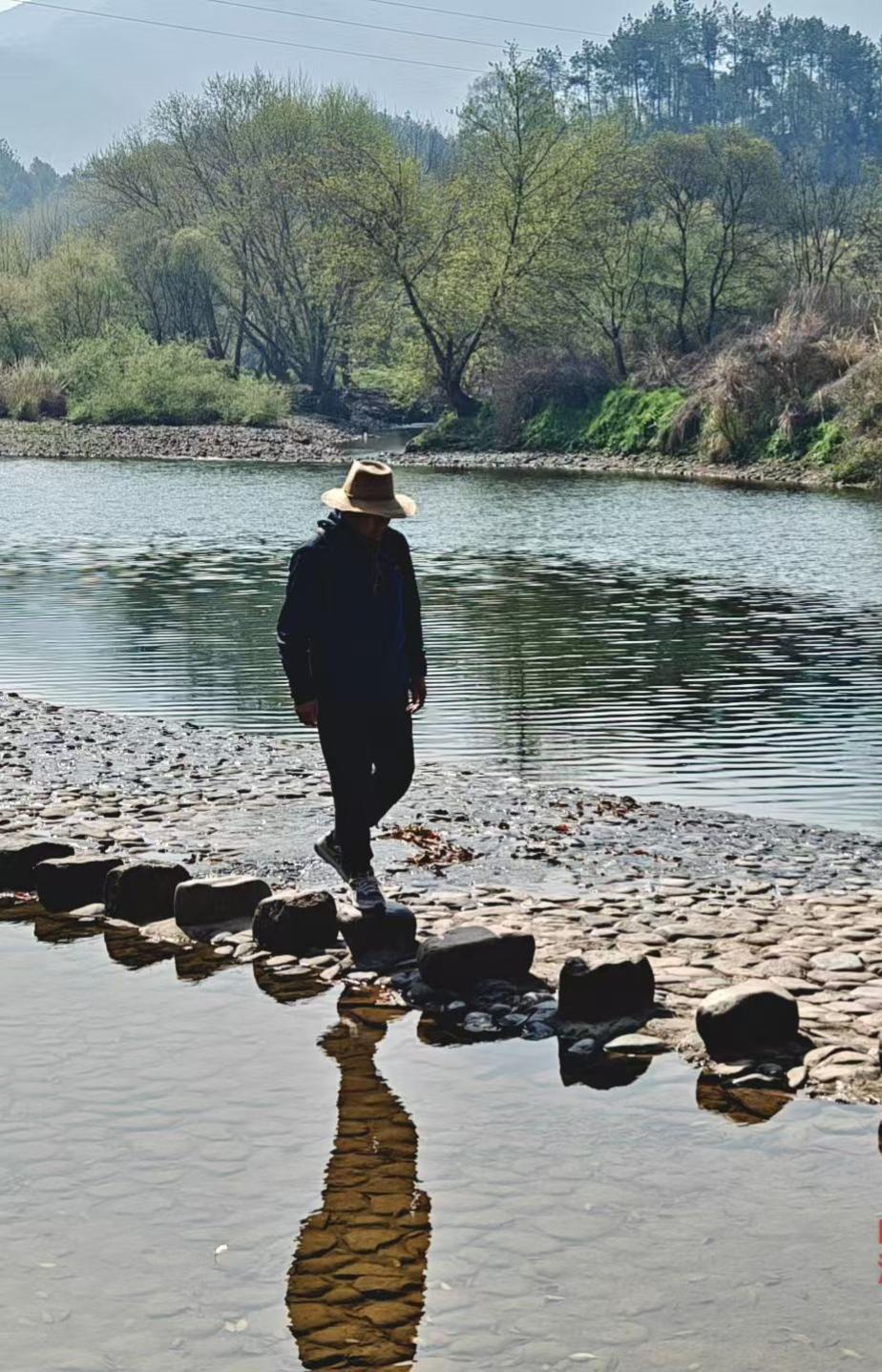 春溪映影，步履从容。踏过浅滩，像走过一段温柔的岁月，眼前的山水，都藏着安宁的味道