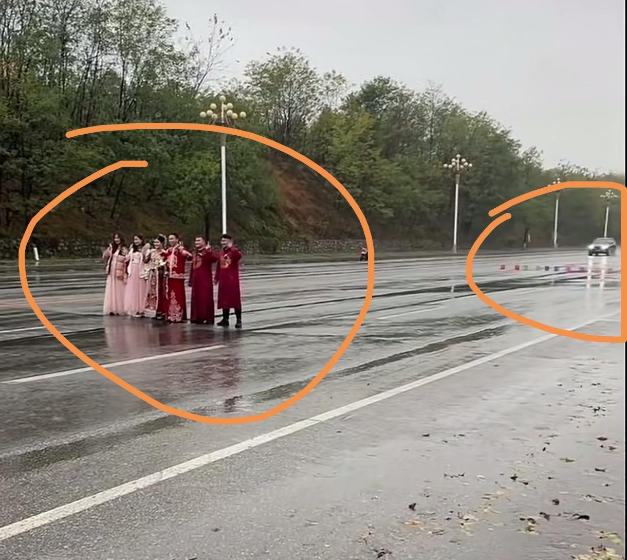 一对夫妻结婚当天，主角加配角一起站在马路中间摆拍，后面还堆放着一排烟花来衬托氛围