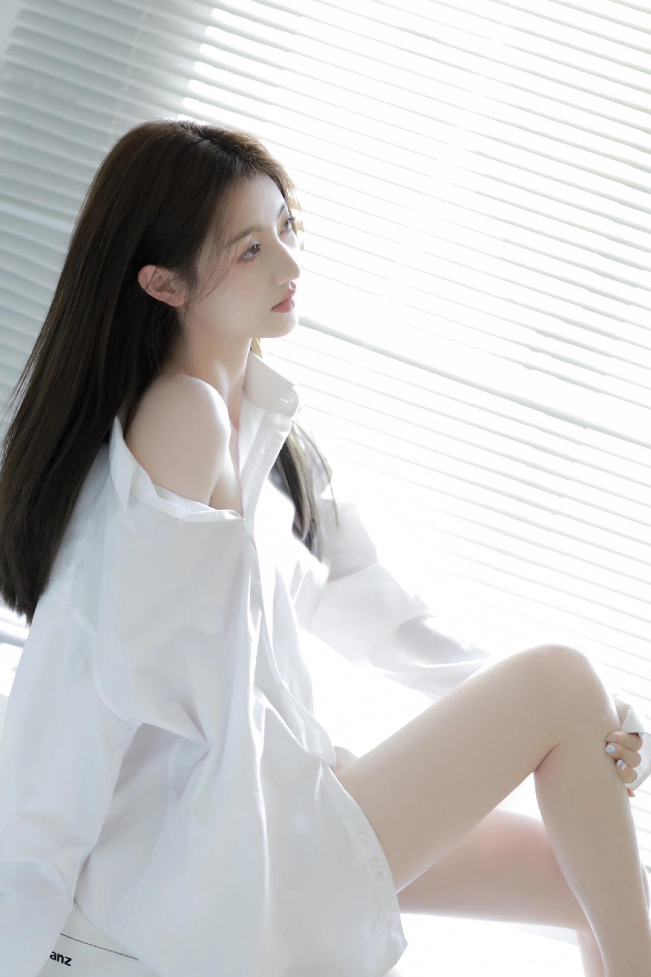 白衬衫滑落肩头，在柔光里晕开一抹温柔的留白