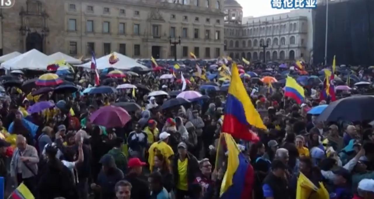 哥伦比亚广场上抗议人群高举国旗、撑伞聚集，巴拿马街头游行队伍举着红色标语横幅呐喊