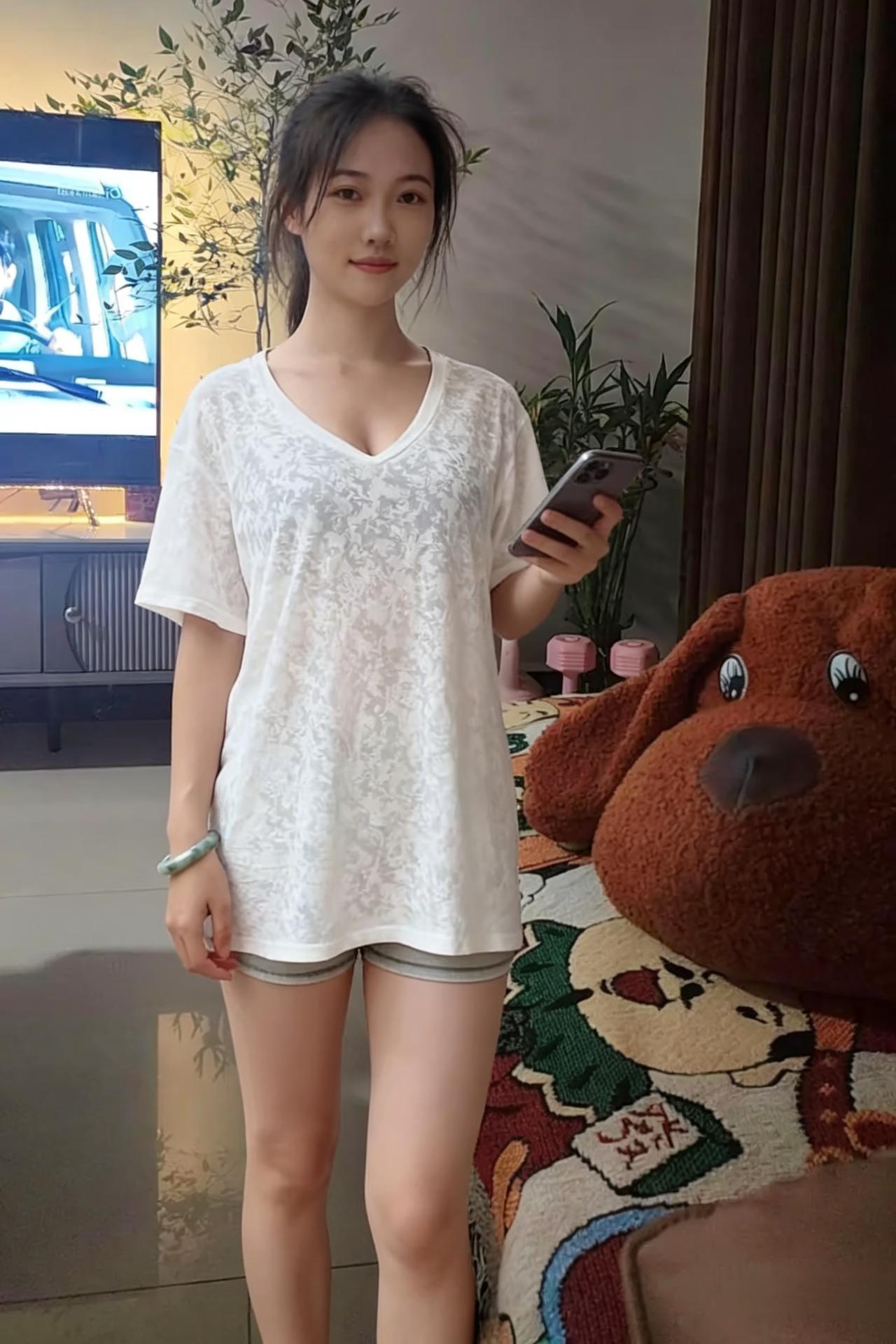 客厅的光，是揉碎的暖黄
电视的光，在她身后晃成模糊的色块
白T恤松松垮垮，罩着她