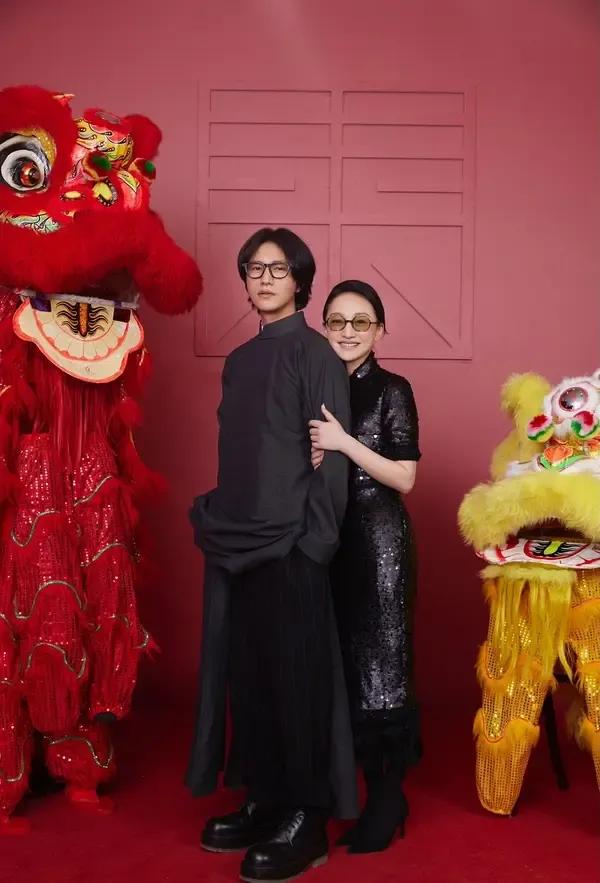 陈坤和周迅新年合照，两人的感情真的很好，陈坤身穿一件黑色长衫，戴着一副黑框眼镜，