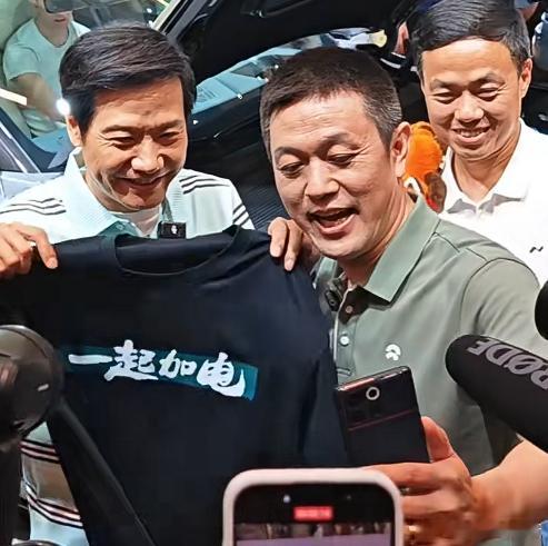 雷军打卡 “蔚小理” 展台，给李斌、何小鹏、李想各送上一件定制 T 恤雷军送李想