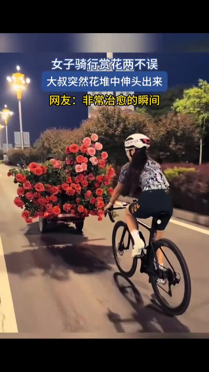 女子骑行赏花两不误，大叔突然花堆中伸头出来。
网友：非常治愈的瞬间。