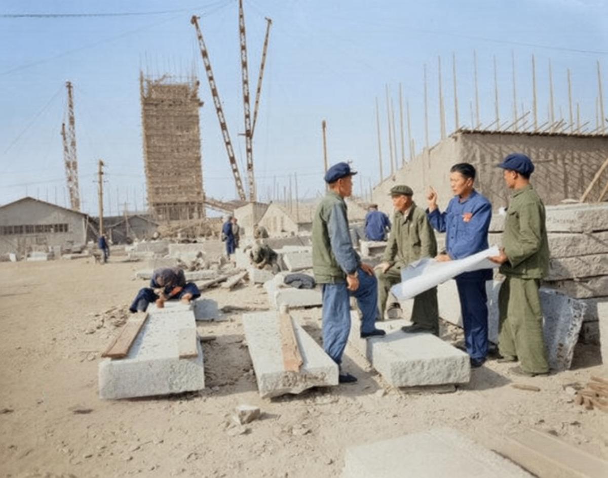 1956年，人民英雄纪念碑建设现场，几位身着工装、头戴解放帽的工程技术人员围站在