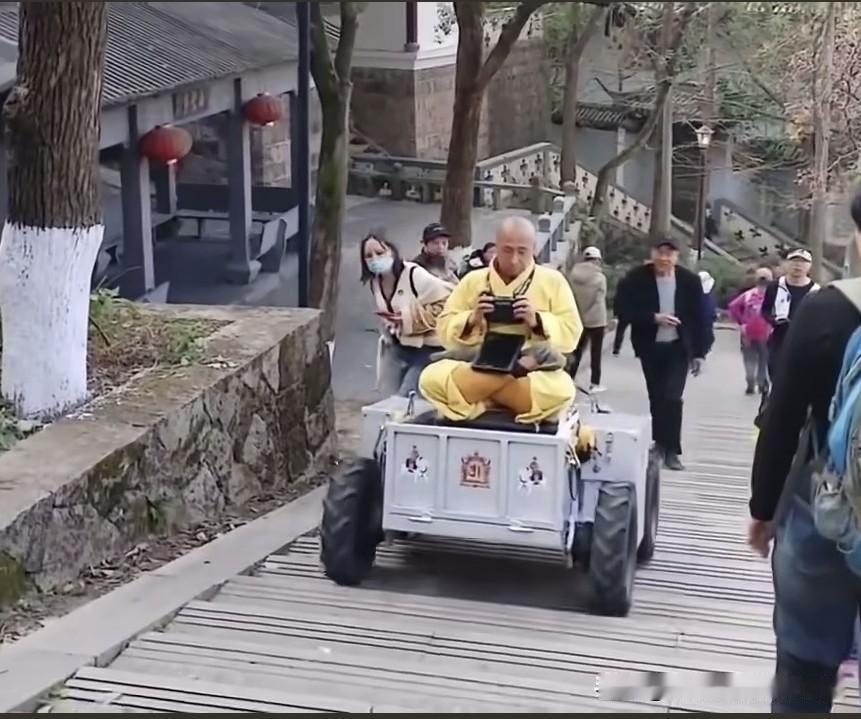 本以为是云游修行，结果是科技上山。

黄衣师傅盘腿坐在自制四轮小车上，顺着木栈道