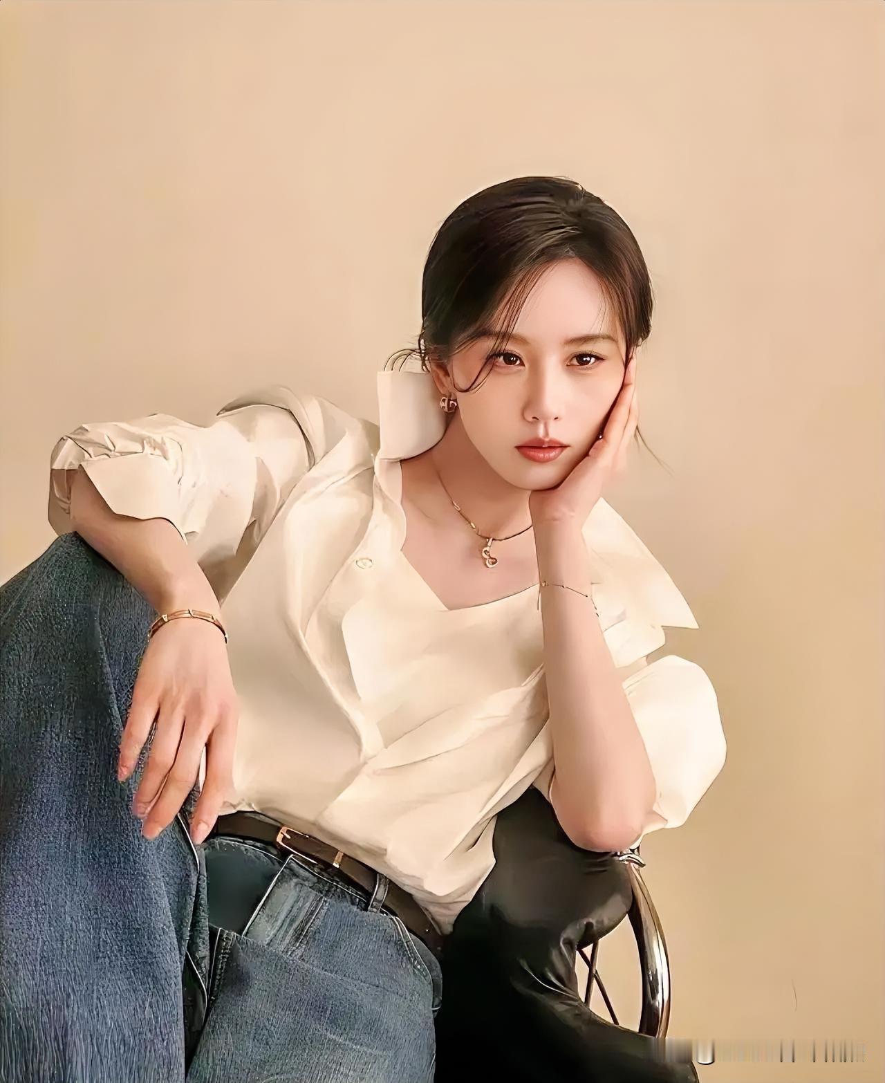 素白衬衫慵懒垂落，丹宁蓝与暖黄背景交织出清闲。指若柔荑轻托香腮，眸光流转间，定格