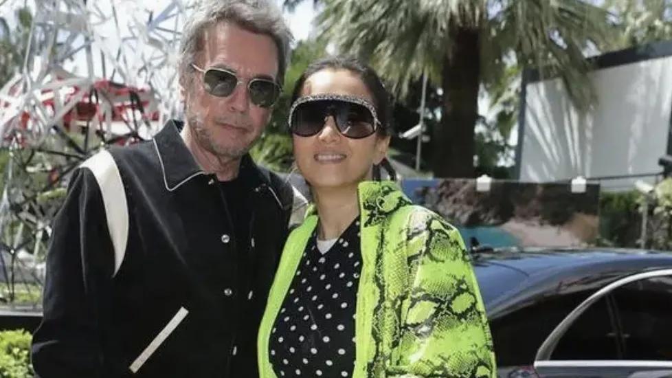 巩俐与她的外国伴侣携手亮相，两人气质相得益彰，尽显般配之美。巩俐身着一袭绿色蛇纹