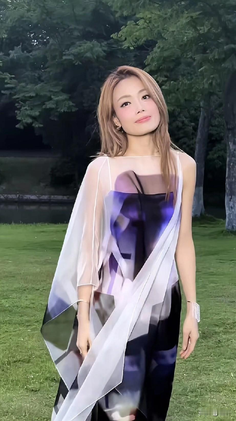 容祖儿夏日清新穿搭，白色透视裙摆，自然绿意背景，轻松自在。