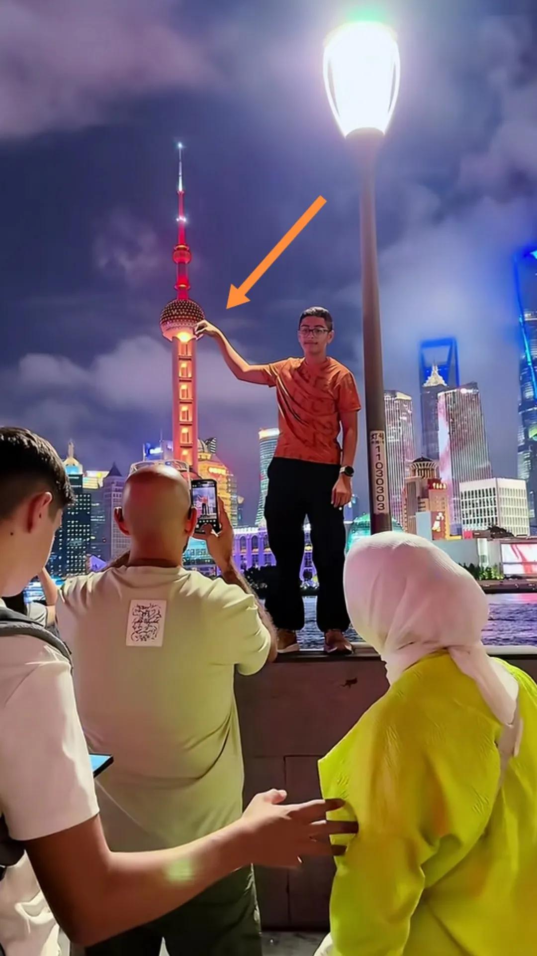 上海外滩老外伸手摘东方明珠塔“夜明珠”。