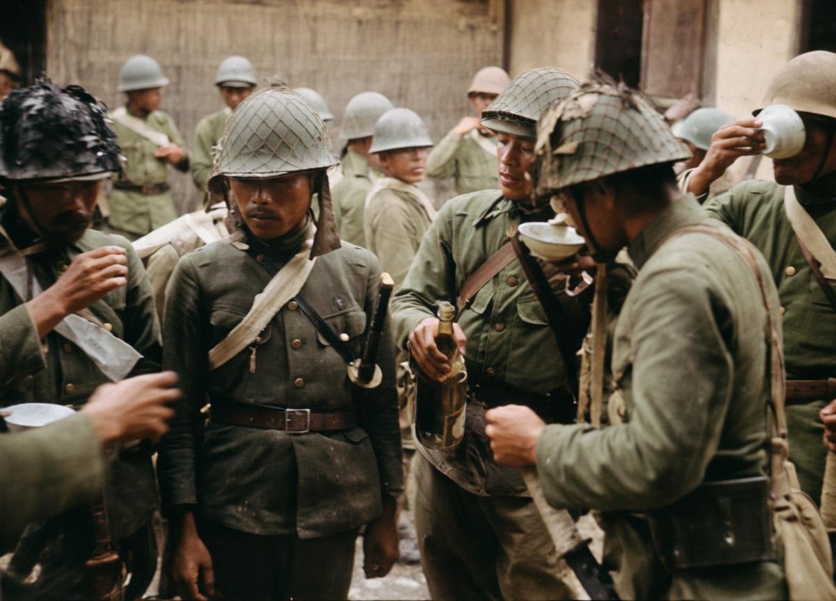 抗日战争时期，侵华日军在作战间隙于乡村民居前集合休整，前方的日军头戴带有网状伪装