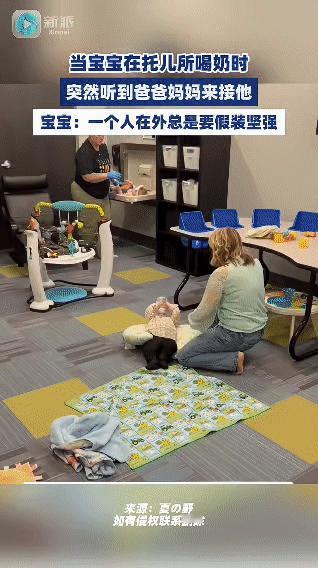 在国外托儿所里，一个宝宝正躺在舒适的垫子上喝奶，突然听到爸爸妈妈来接他的动静。前