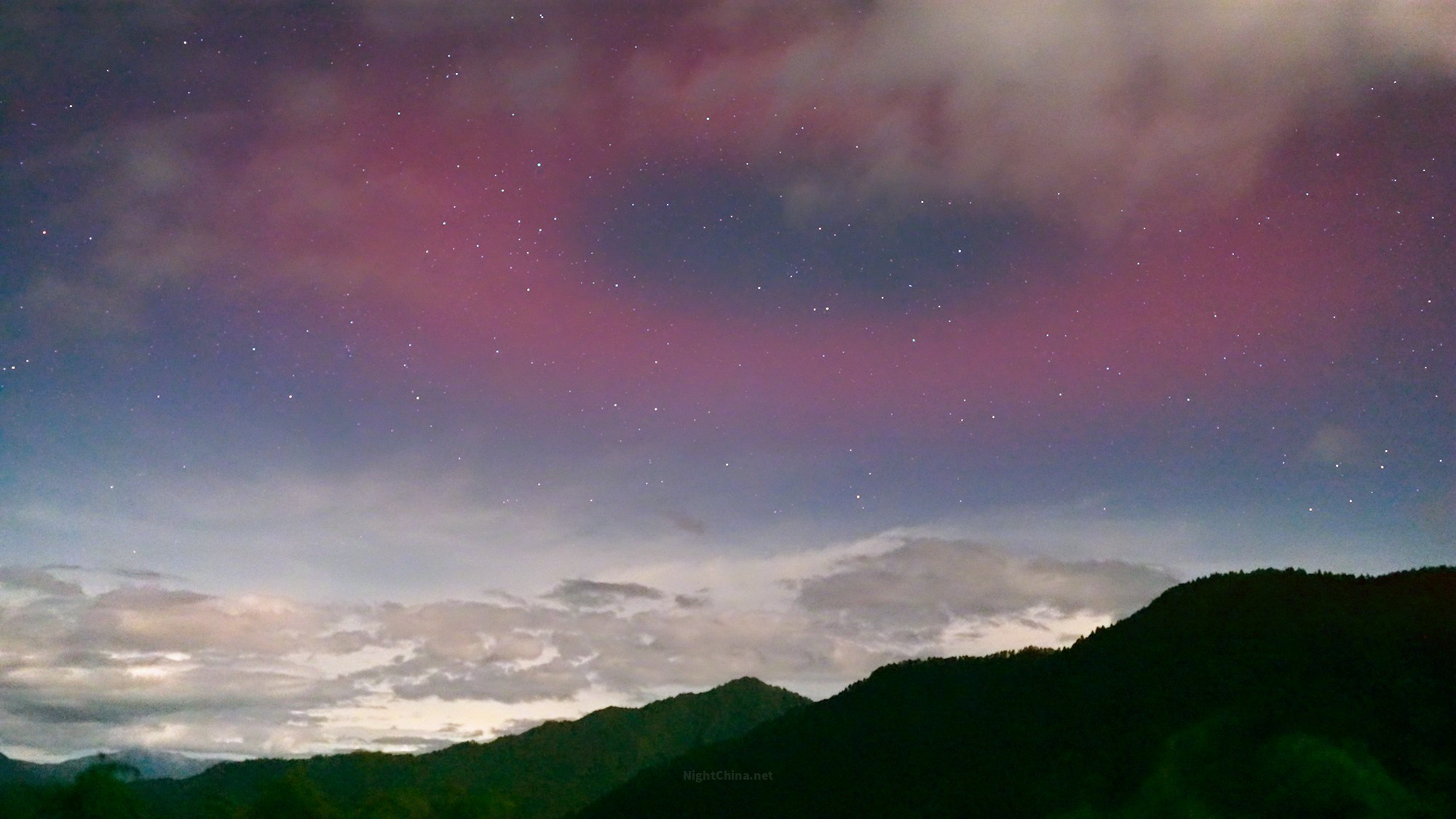 夜空之上，一片玫瑰色的光晕悄然铺开，像是谁把颜料泼进了大气层最高的那一页，轻柔，
