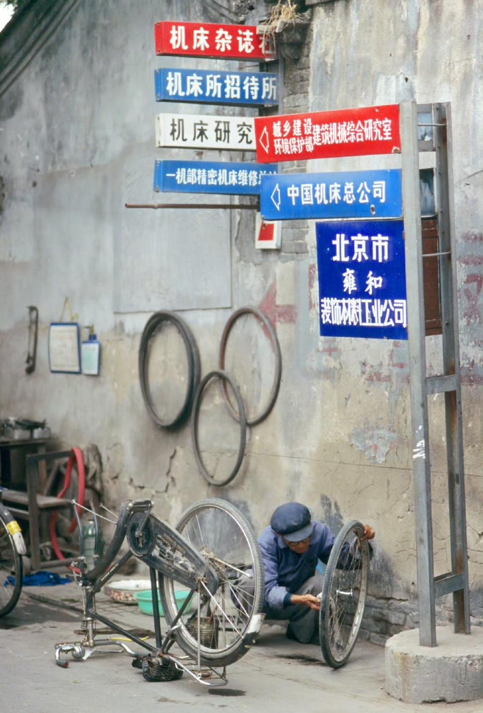 1993年，北京自行车修理摊，路牌上应该是附近的大型单位。
