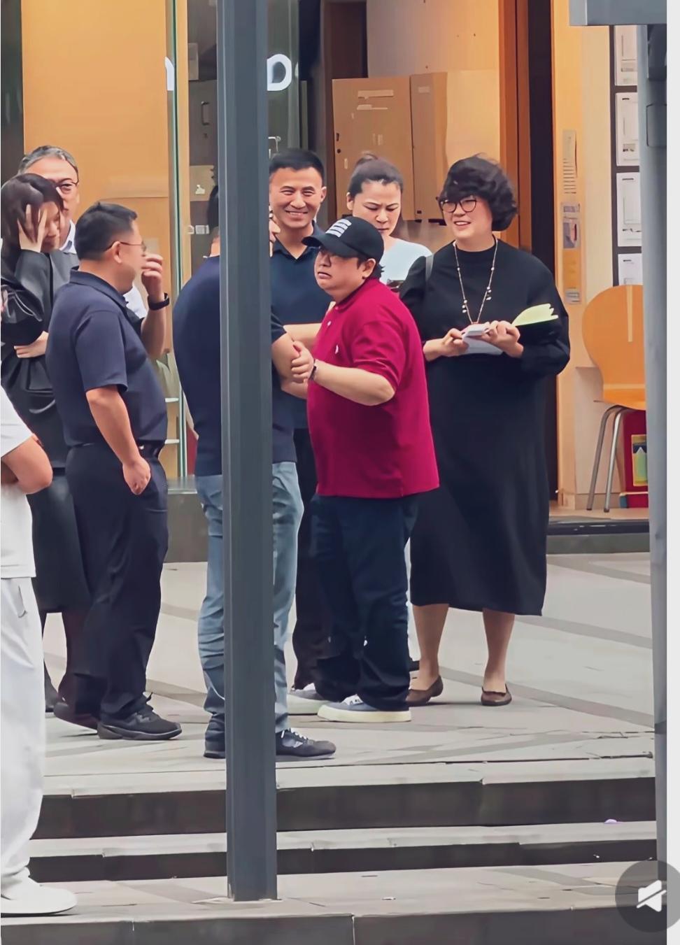 韩红现身成都，身穿红色体恤，头戴黑色棒球帽，整体穿搭低调休闲。
她站在人群中心，
