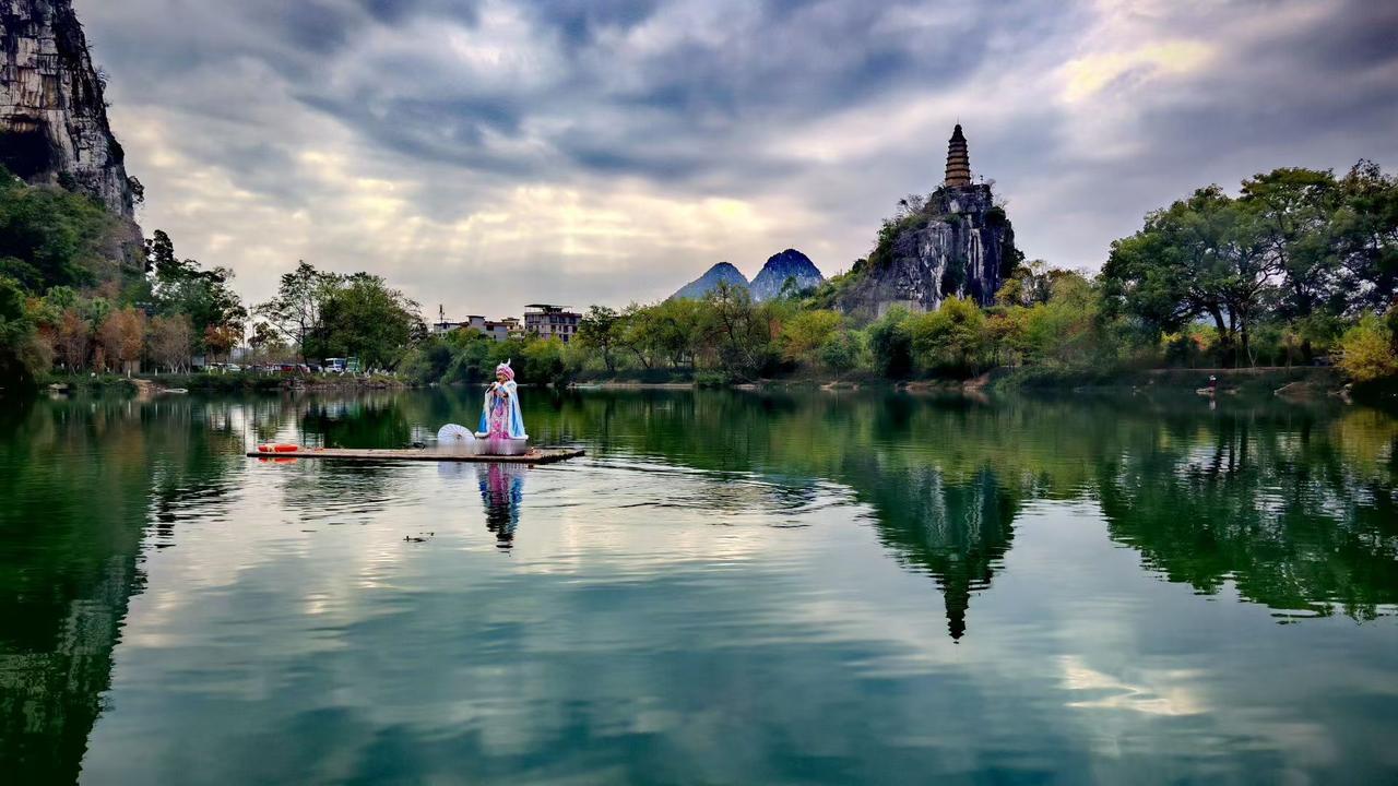 ✨云絮在蓝天织着绵密的梦，湖水盛着群山与古塔的剪影，戏中人立在筏上，像从岁月深处