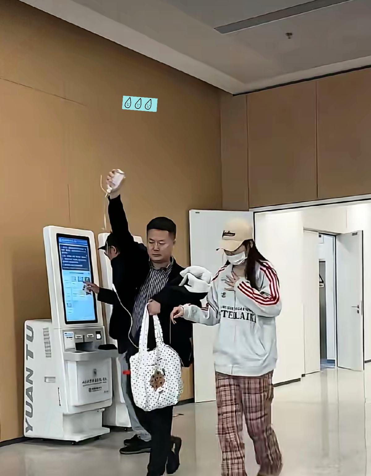 一名男子，一手举着输液瓶，一手提着包，寸步不离地跟着身旁的年轻女孩，知道男子和女