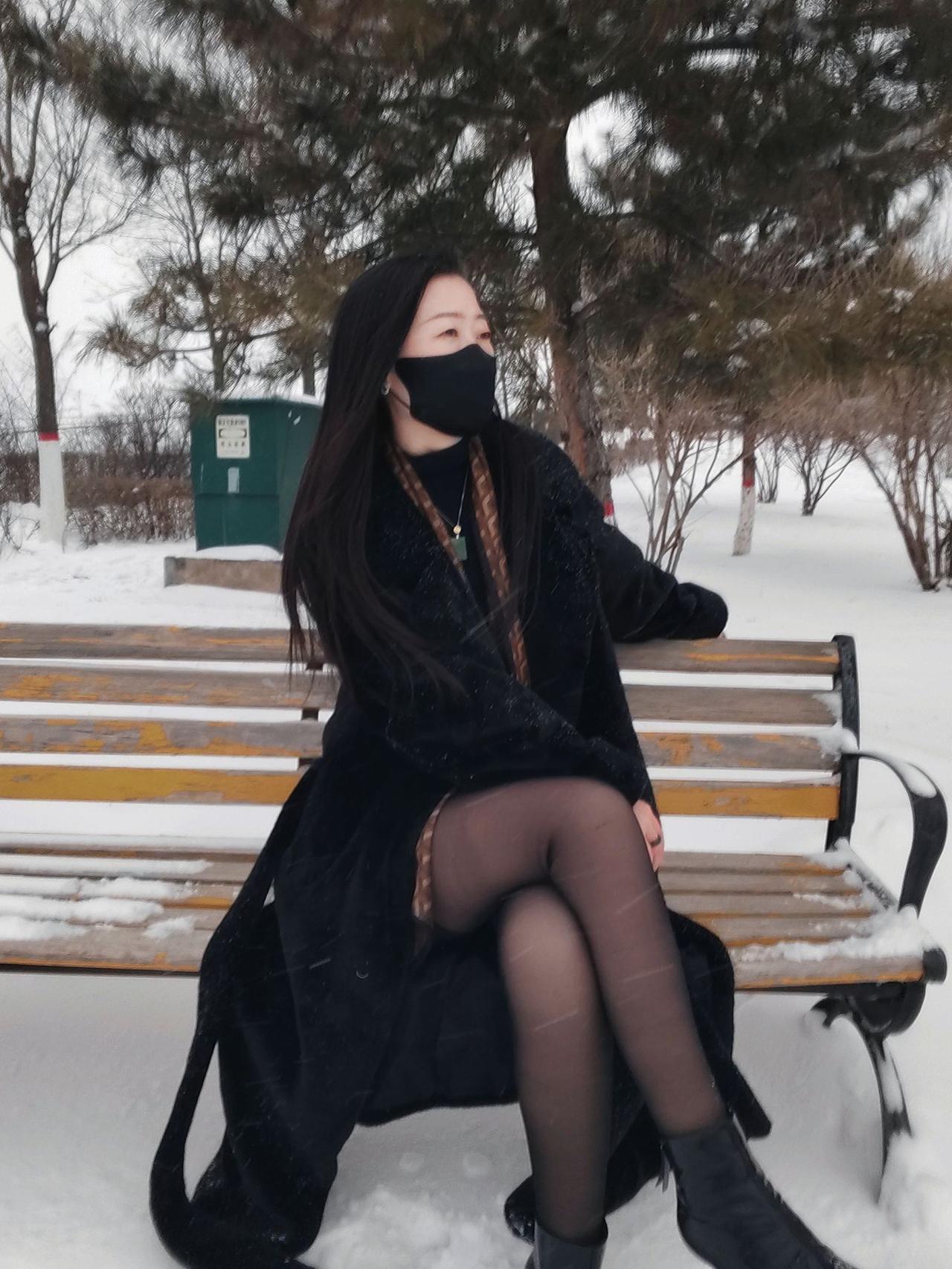 冬日雪景中的时尚穿搭，黑色大衣与围巾的搭配，尽显优雅与温暖。