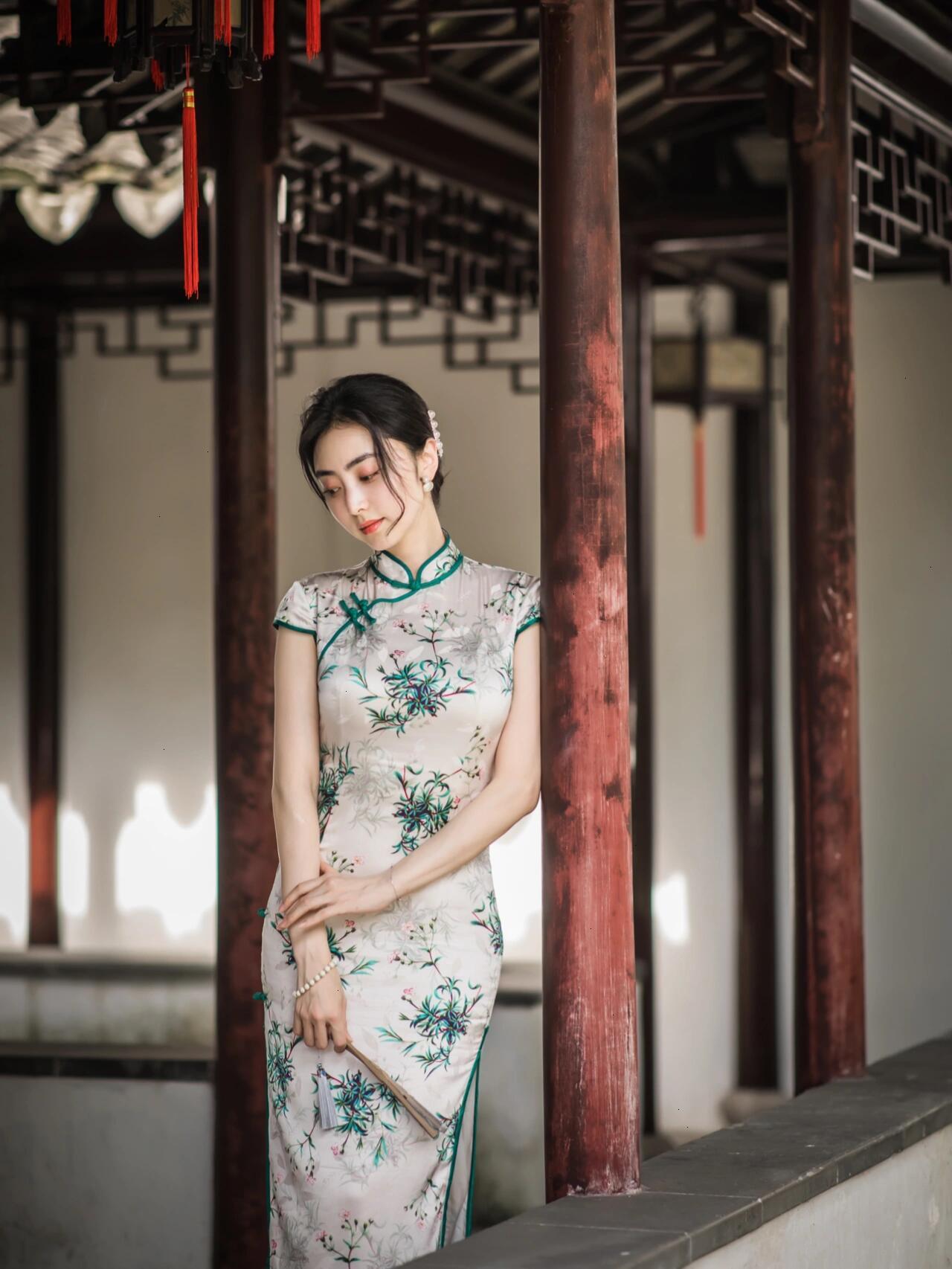 黛瓦朱栏里，竹枝曳在素色旗袍的襟边，腕间碎光与鬓侧银钗，都浸在江南的软风里。窗棂